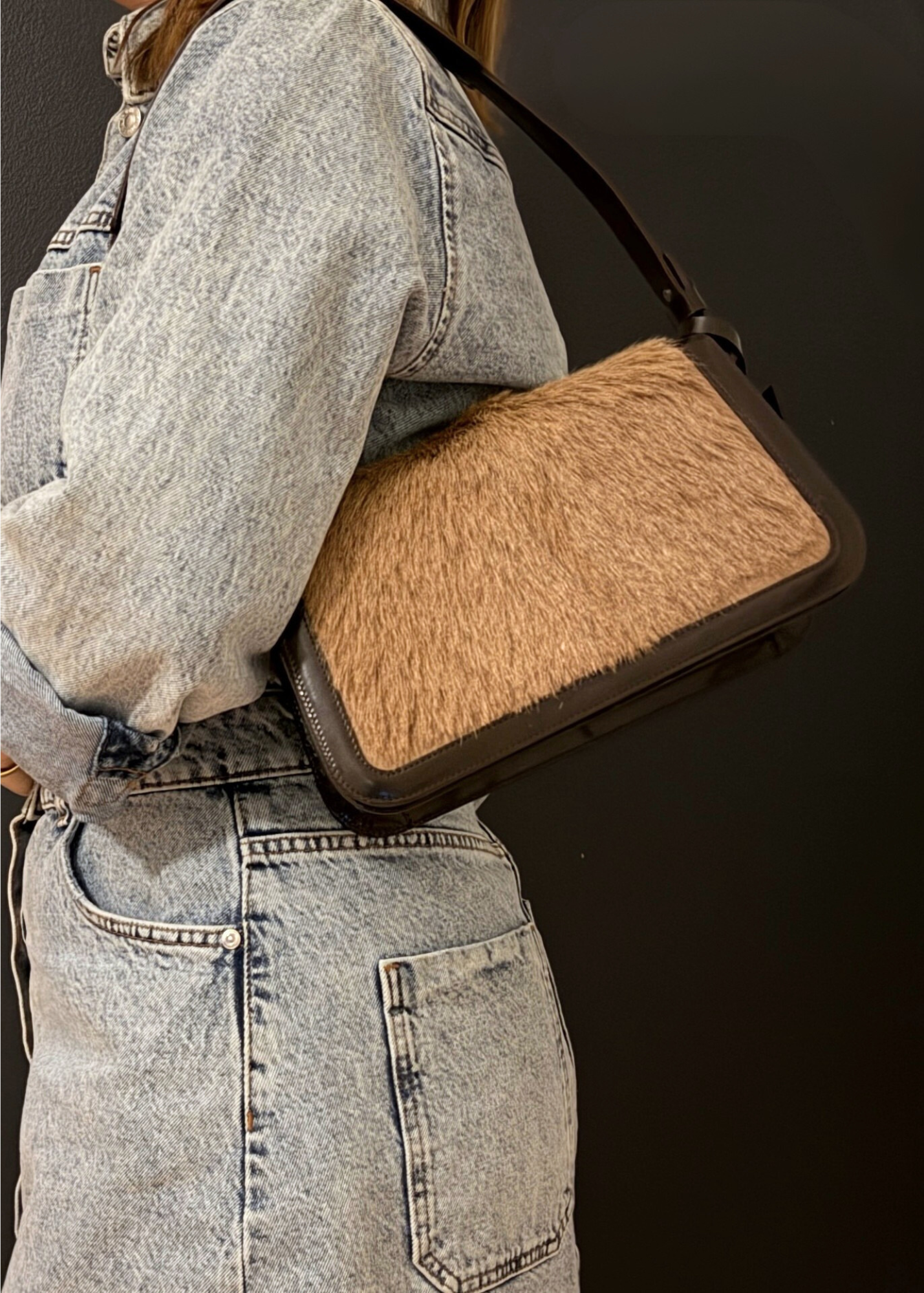Person wearing a textured brown bag over shoulder against a dark background