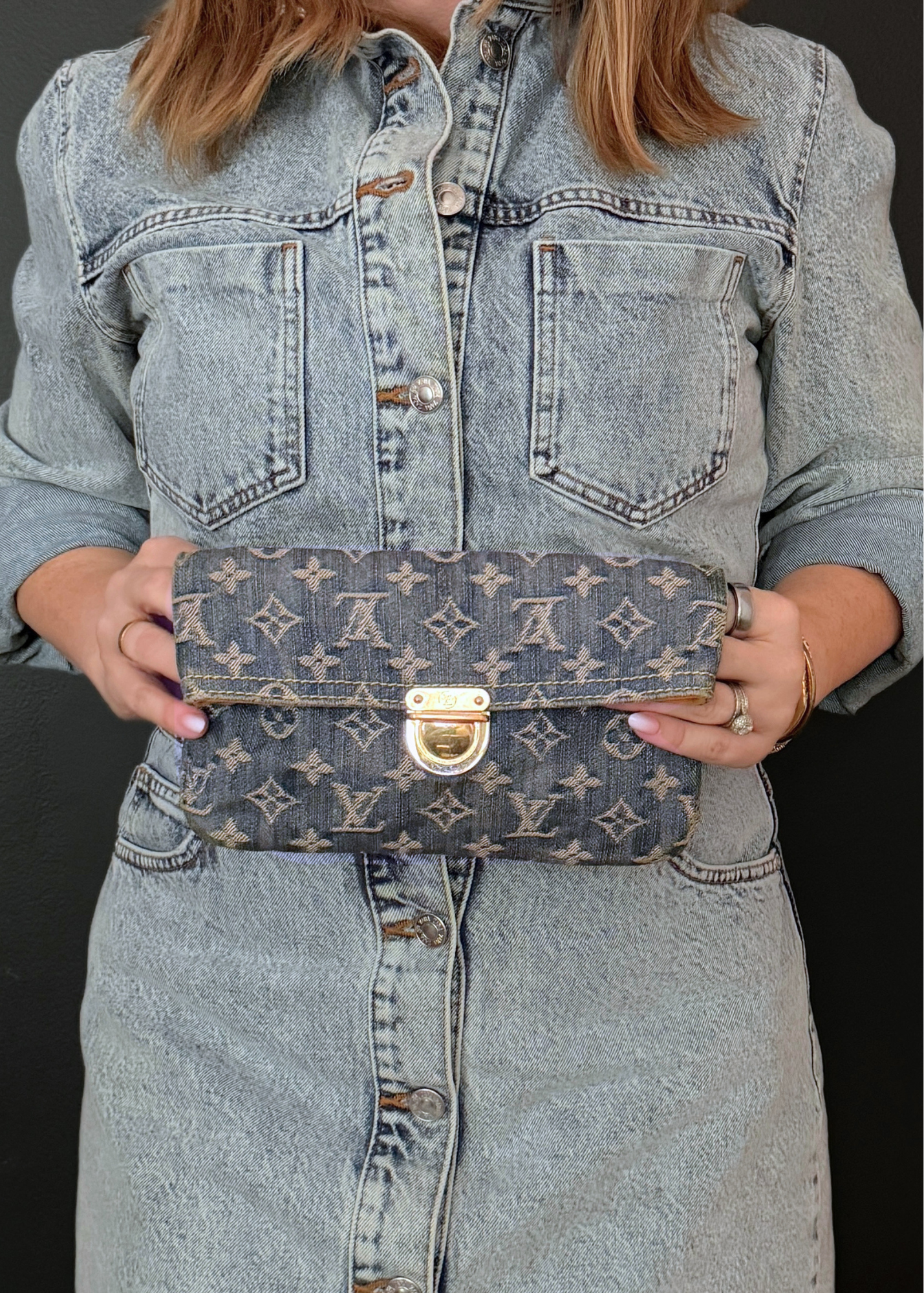 Person holding a Louis Vuitton monogram bag against a black background