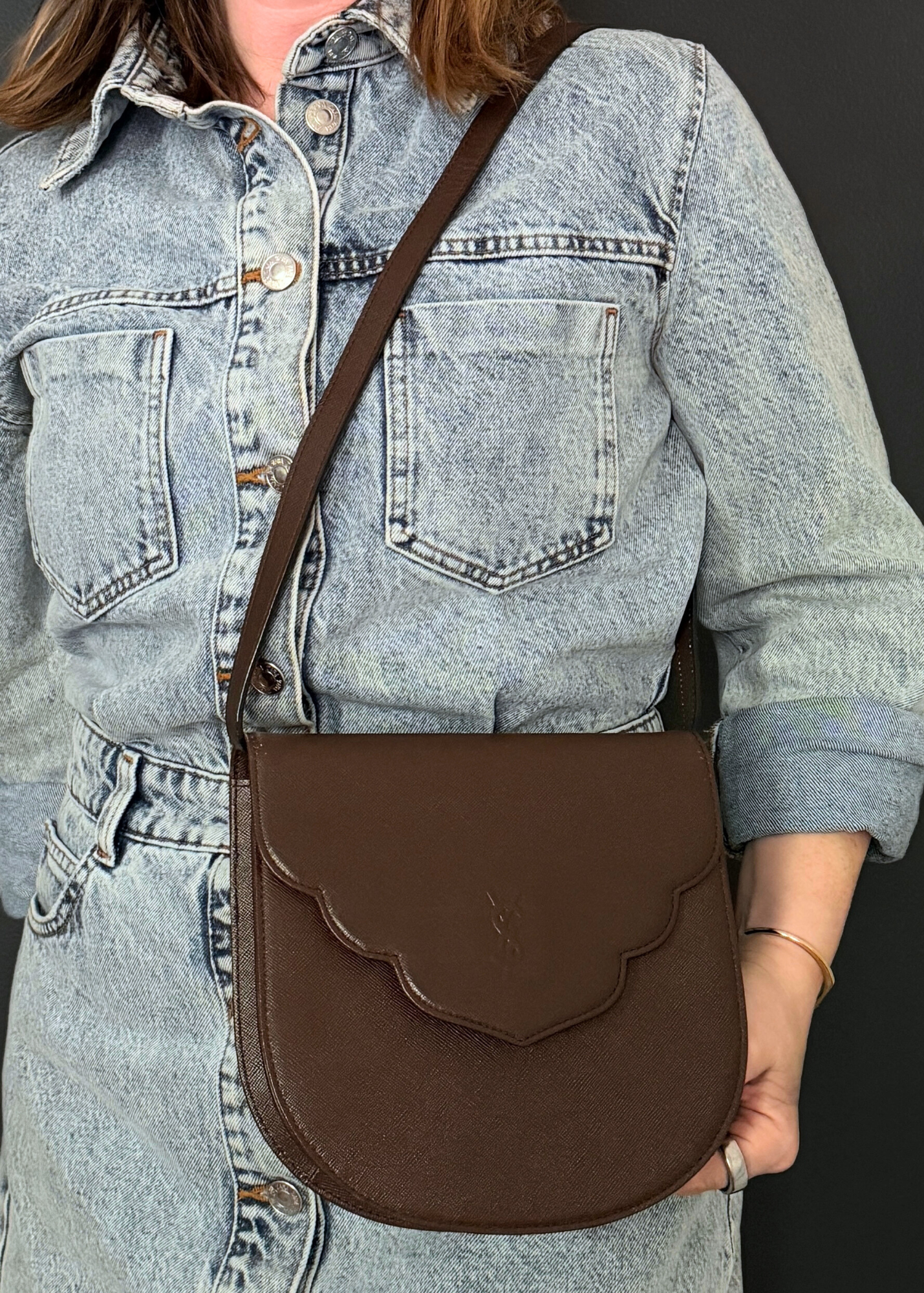 Person wearing a vintage brown leather Yves Saint Laurent crossbody bag