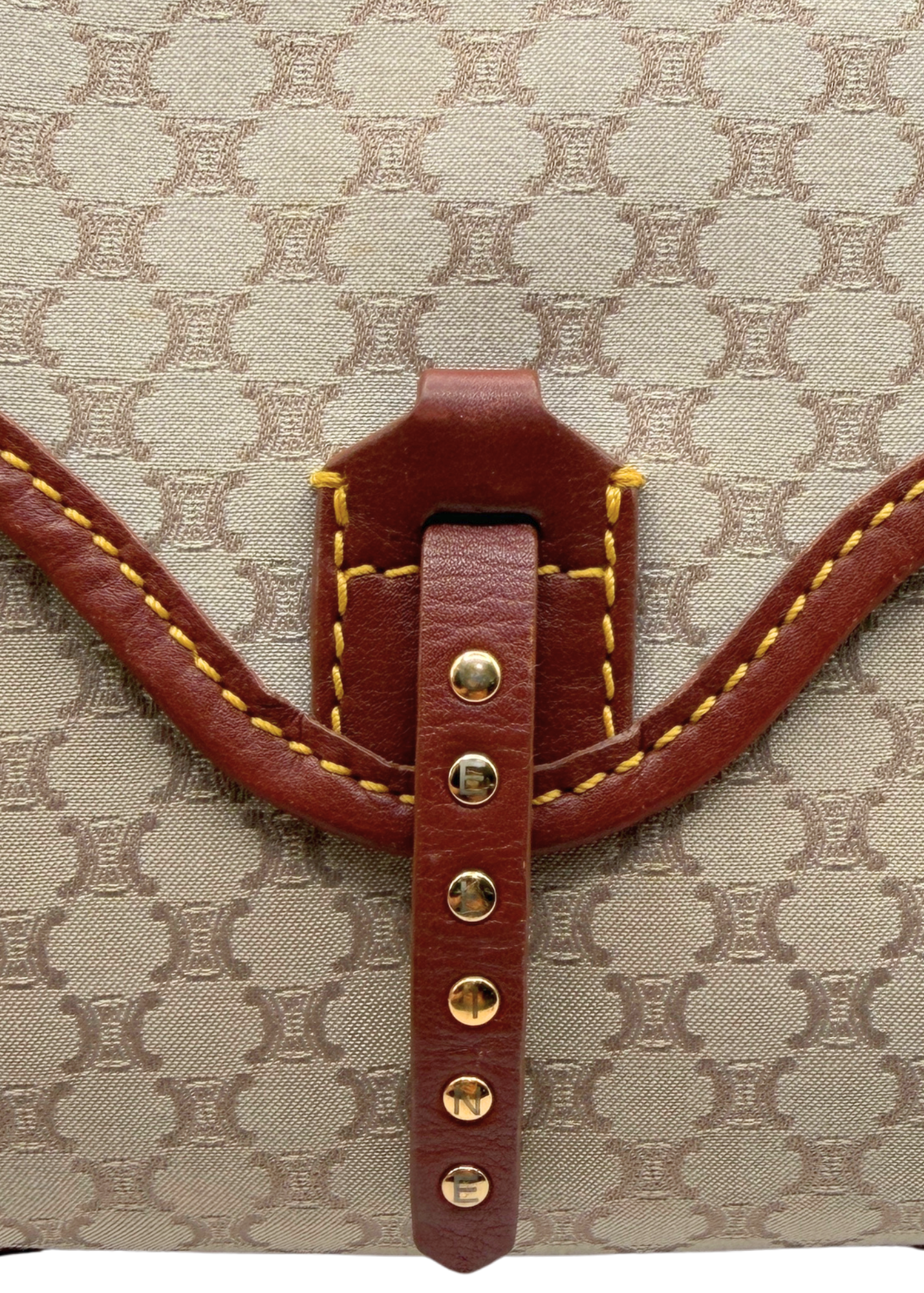 Close-up of a beige and brown vintage Celine triomphe monogram canvas bag with a brown leather strap closure and gold-tone studs.