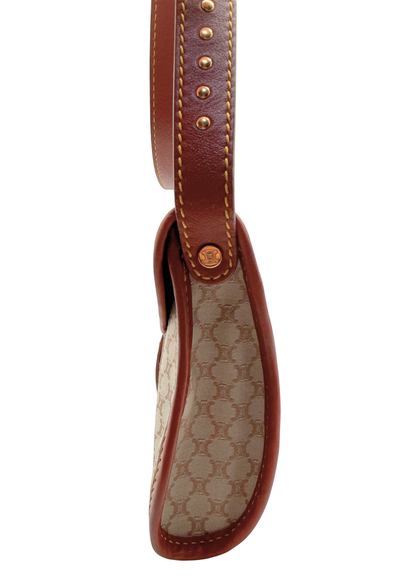 Close-up of a vintage Celine shoulder bag strap showing the brown leather strap with gold-tone studs, contrast stitching, and the beige and brown triomphe monogram canvas side panel.