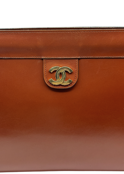 Brown leather handbag with gold CC Chanel logo on a white background