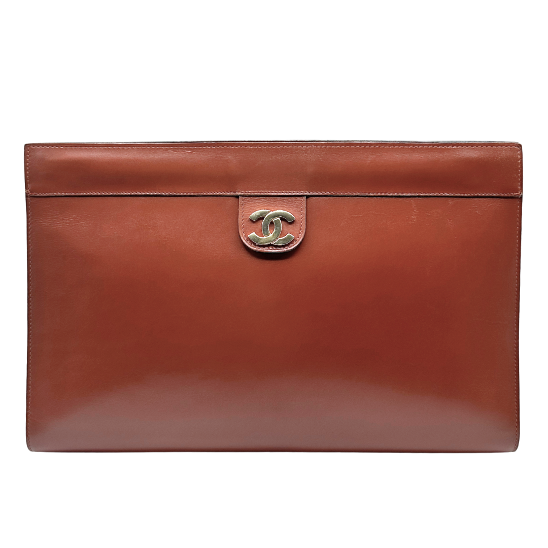 Brown leather clutch bag with Chanel logo on a white background