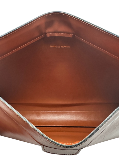 Close-up of a brown Chanel leather clutch with 'Made in France' stamp on a white background