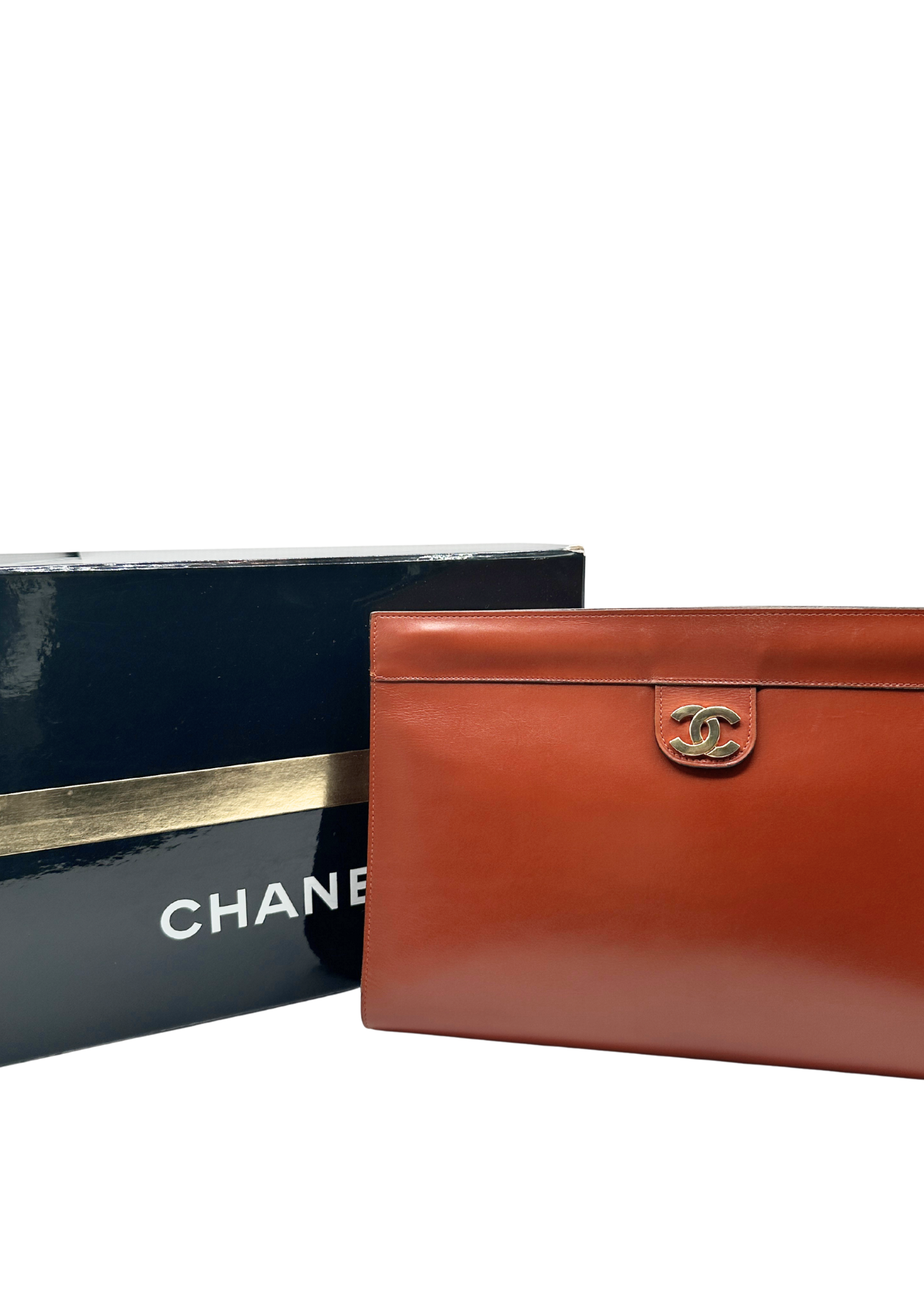 Brown leather clutch with Chanel logo next to a black box with Chanel branding.