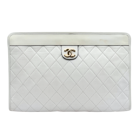 White quilted vintage Chanel handbag with gold hardware on a white background