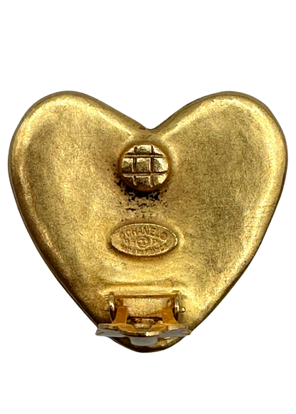 Gold heart-shaped Chanel earrings with a visible brand logo on a white background
