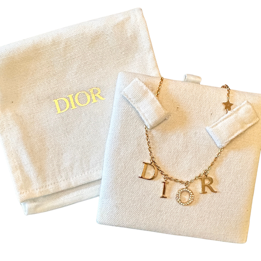 Gold Dior necklace on a branded Dior pouch with a white background