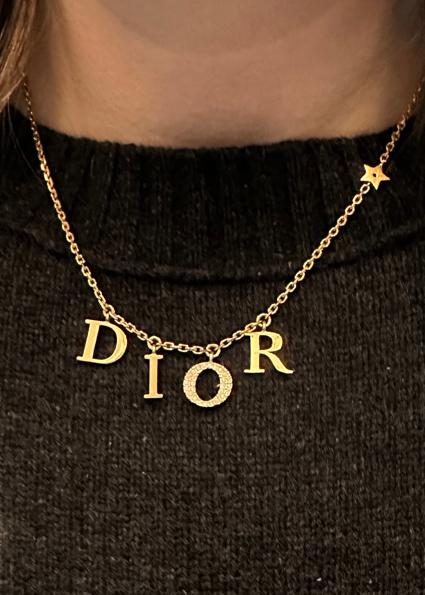 Gold 'Dior' necklace on a black background