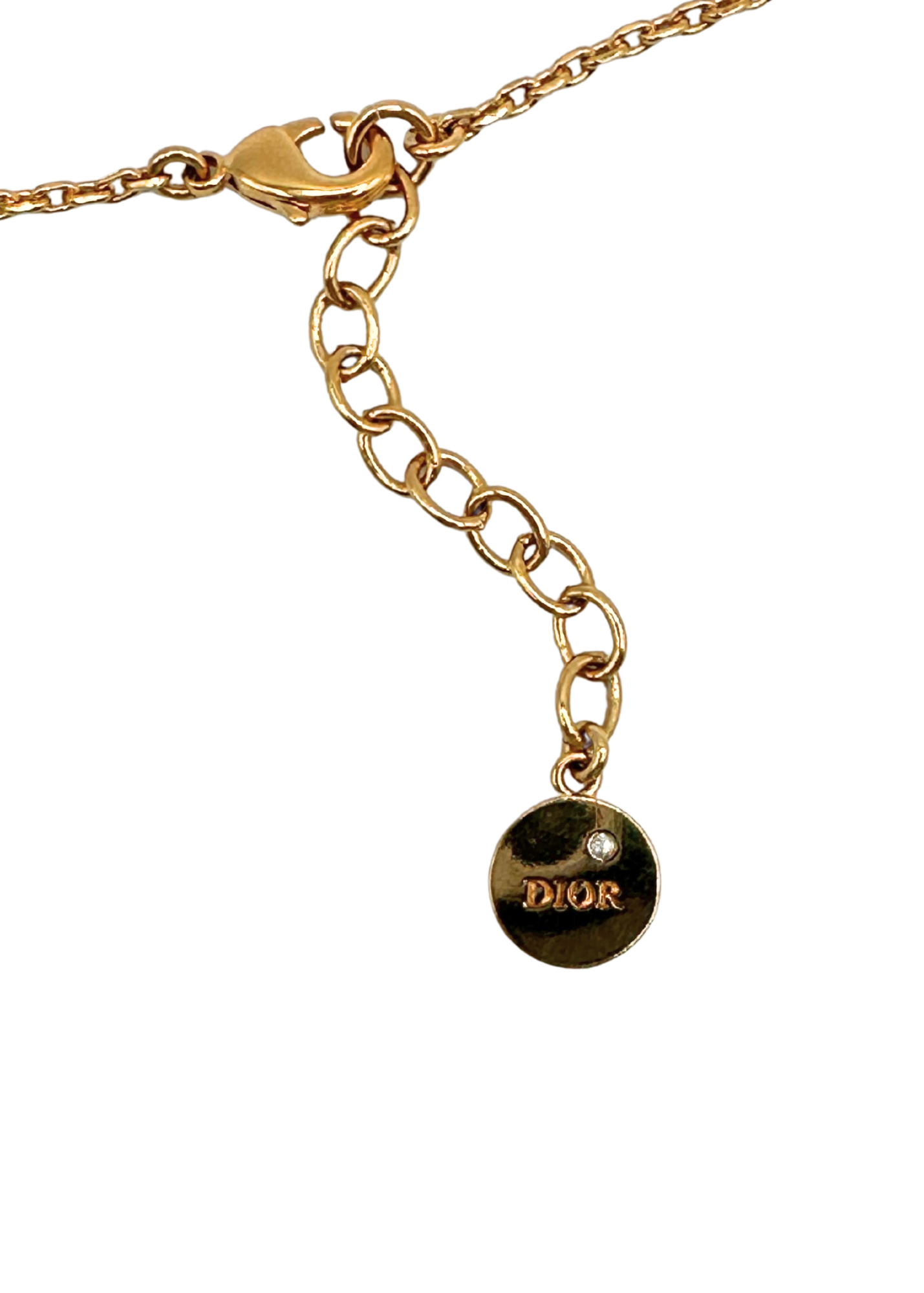 Gold chain necklace with a Dior charm on a white background