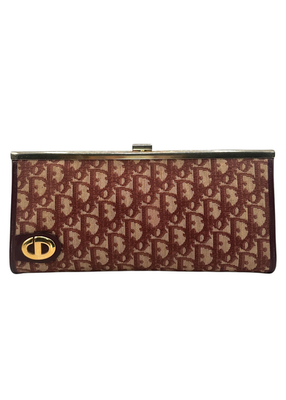 Red and beige patterned clutch bag with gold clasp on a white background