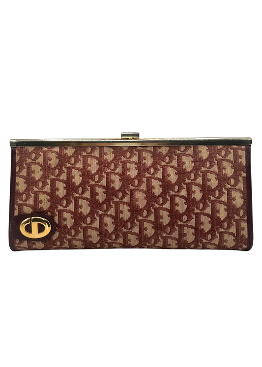 Red and beige patterned clutch bag with gold clasp on a white background