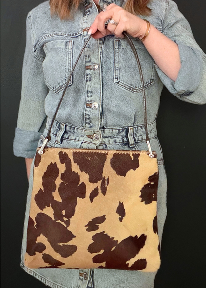 Person holding a cow print vintage Fendi handbag with a denim jacket