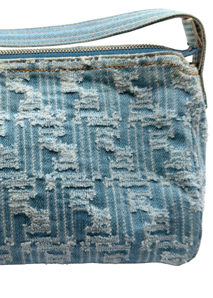 A close-up of a vintage Fendi light blue denim shoulder bag with a distressed, frayed monogram pattern and a matching blue zipper.