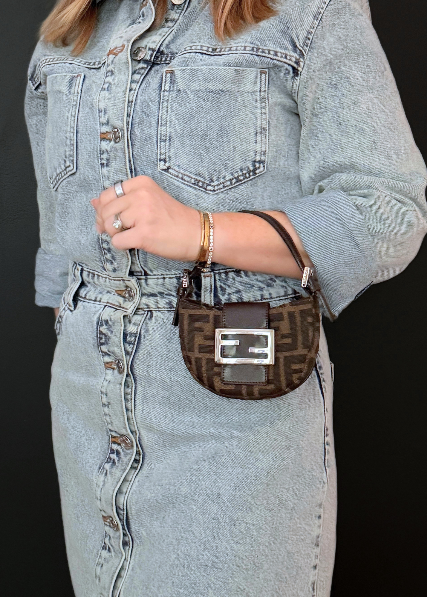 Person wearing a denim jacket and jeans with a vintage Fendi brown zucca patterned bag.