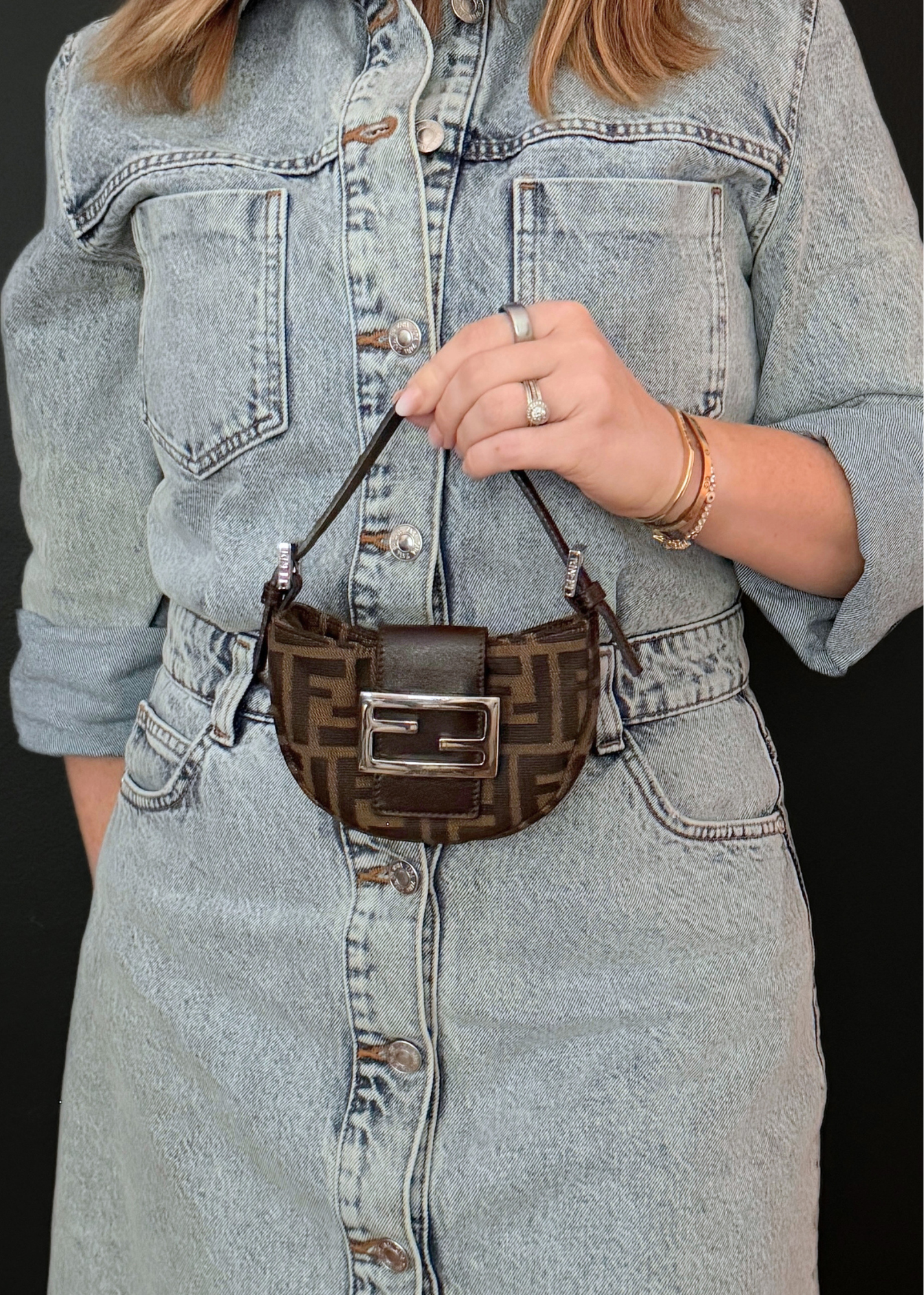 Person wearing a denim outfit holding a vintage Fendi zucca patterned handbag.