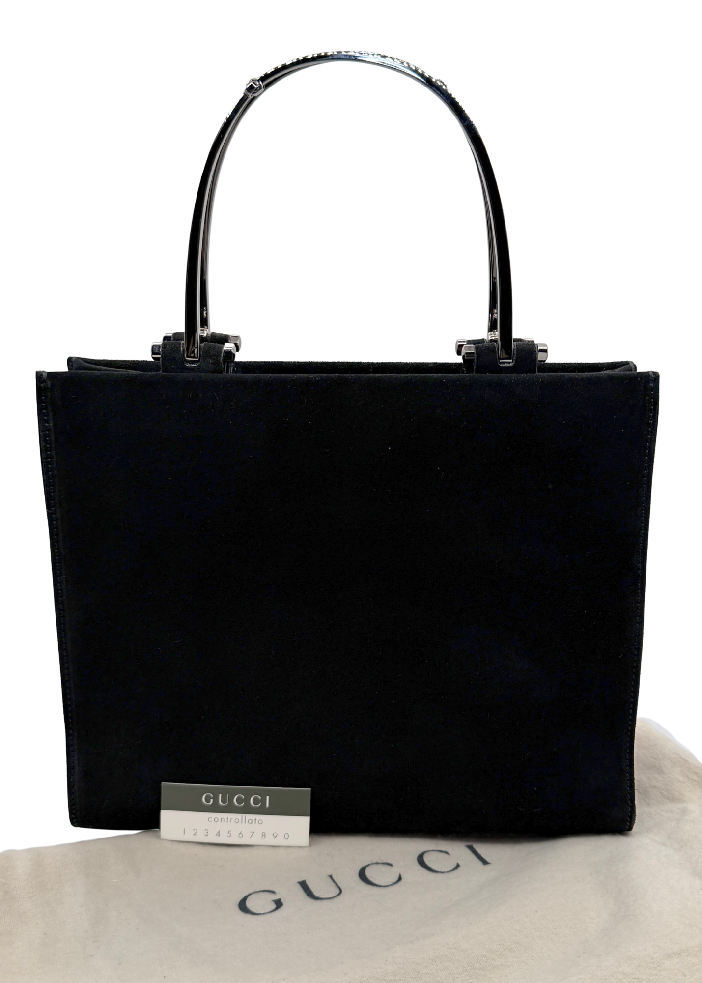 A black Gucci suede tote bag with glossy silver metal horsebit handles, displayed on a beige Gucci dust bag against a white background.