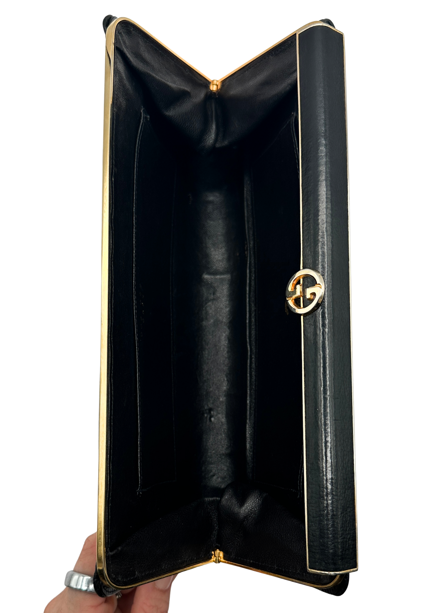 Black Gucci leather clutch with gold trim held open on a white background