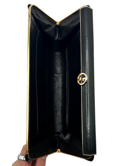 Black Gucci leather clutch with gold trim held open on a white background