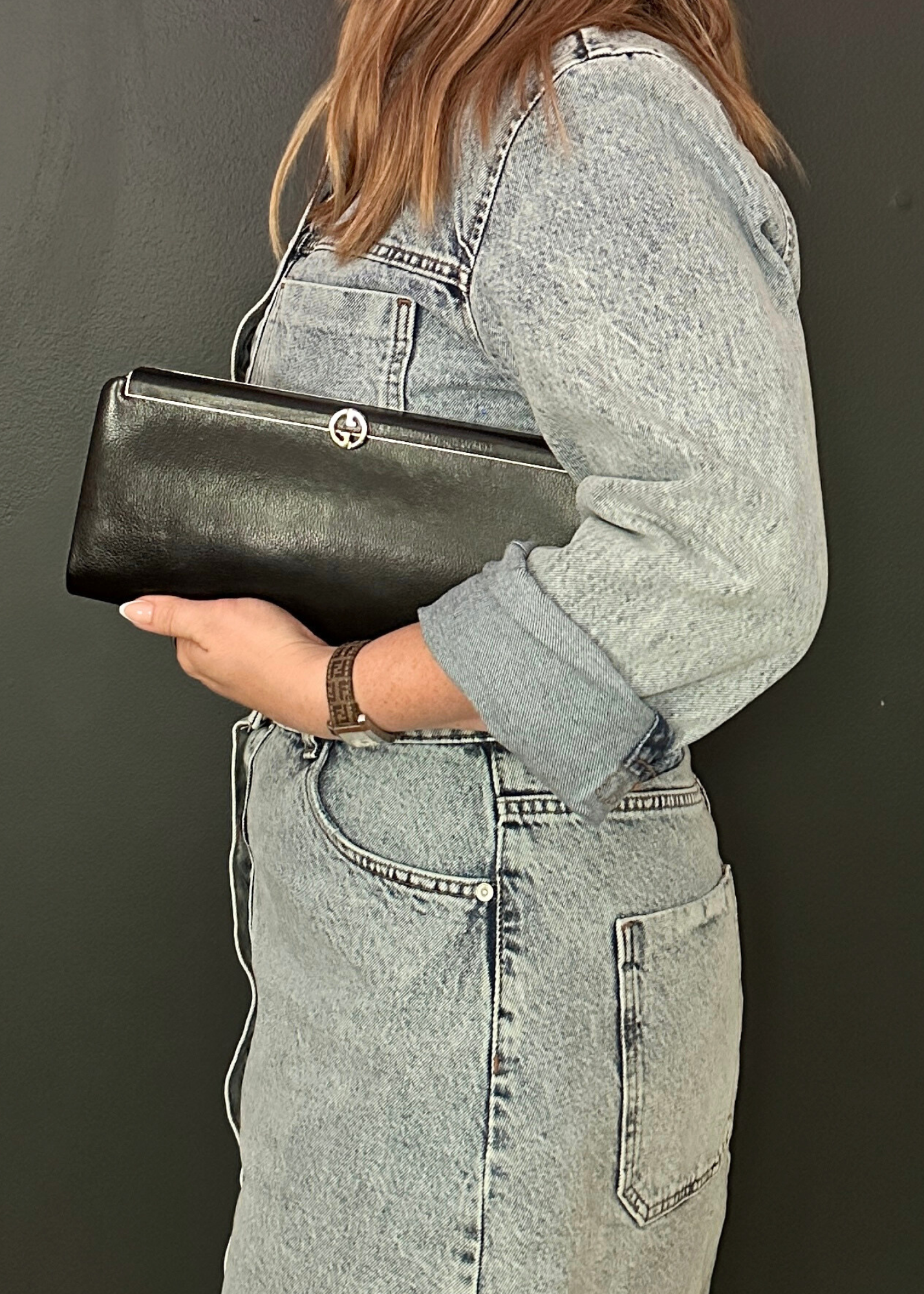 Person holding a black Gcuci clutch with a dark background