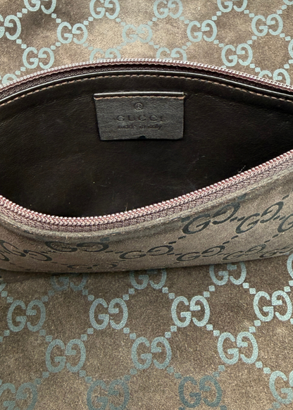 Close-up of an open Gucci zip pouch showing the interior lining and a Gucci leather label inside, with the exterior featuring the classic brown and beige GG monogram canvas.