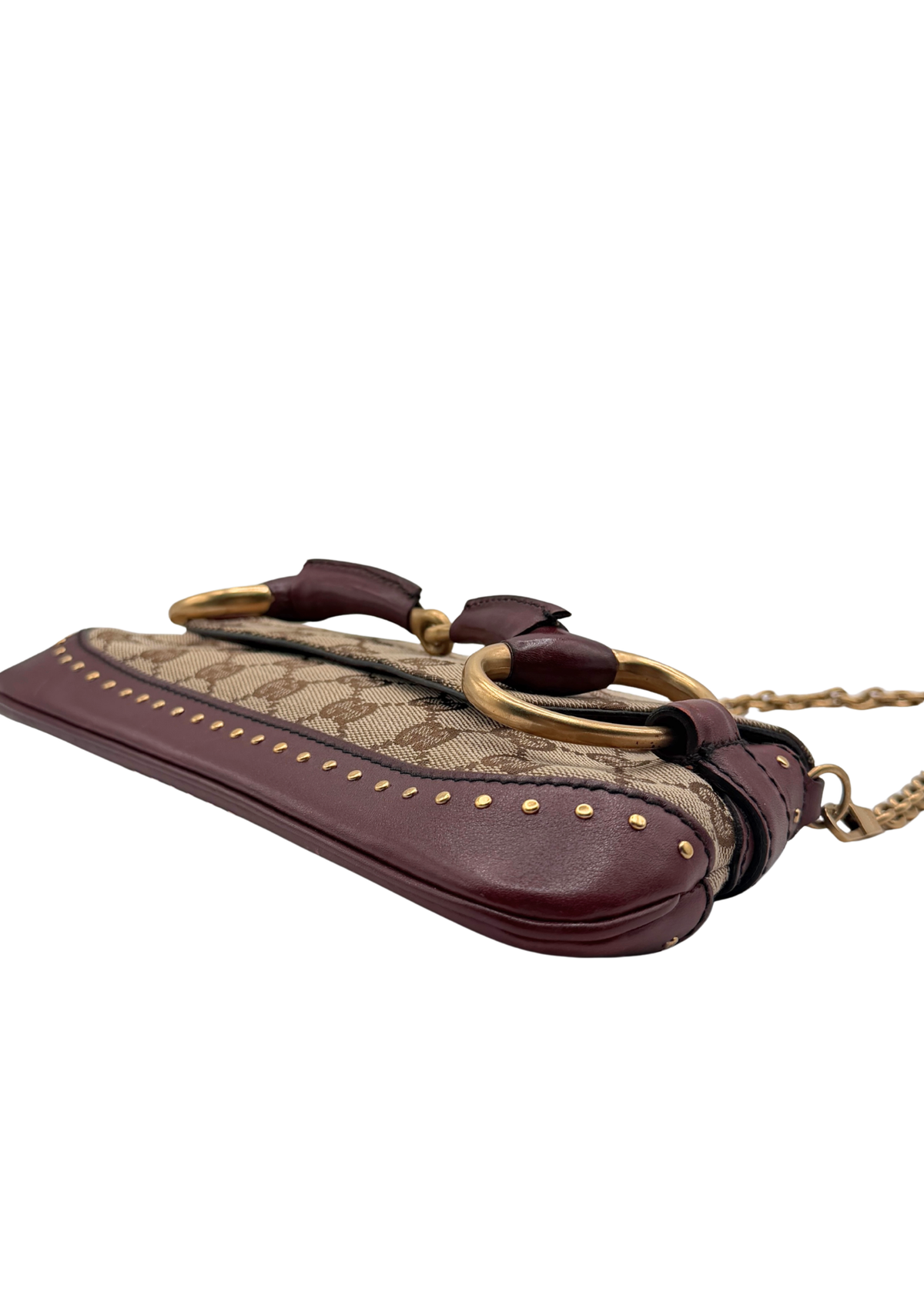 A Gucci Horsebit bag in brown monogram canvas and burgundy leather, featuring gold-tone horsebit hardware and a gold chain strap, shown on a plain white background.
