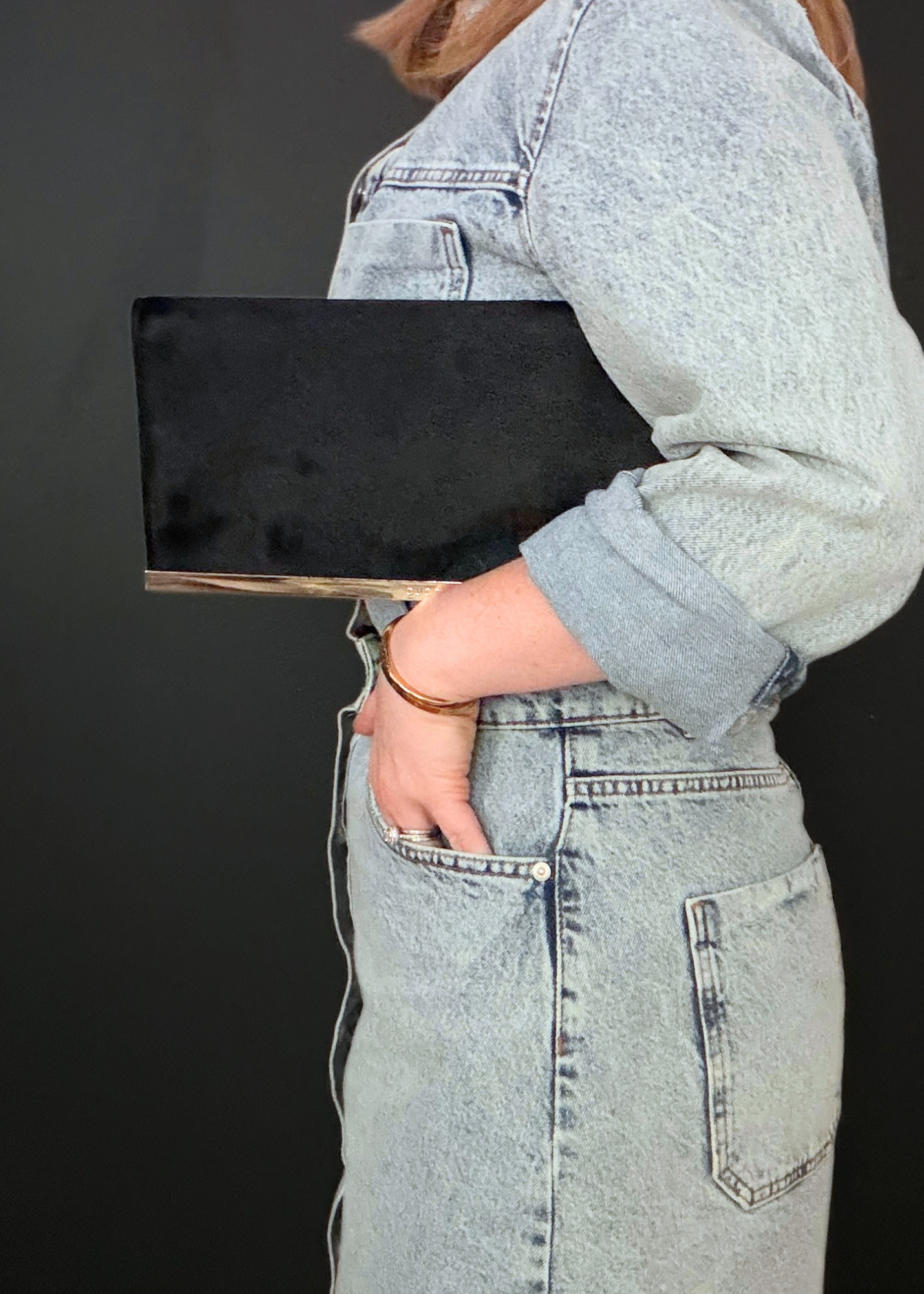 Person holding a black rare vintage Gucci  clutch against a dark background