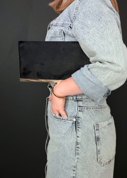 Person holding a black rare vintage Gucci  clutch against a dark background