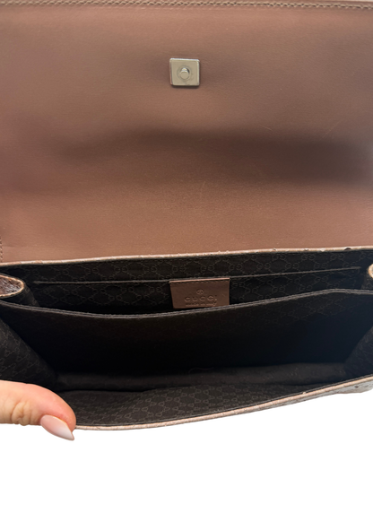 Close-up of a brown leather bag with a visible Gucci brand logo on a white background