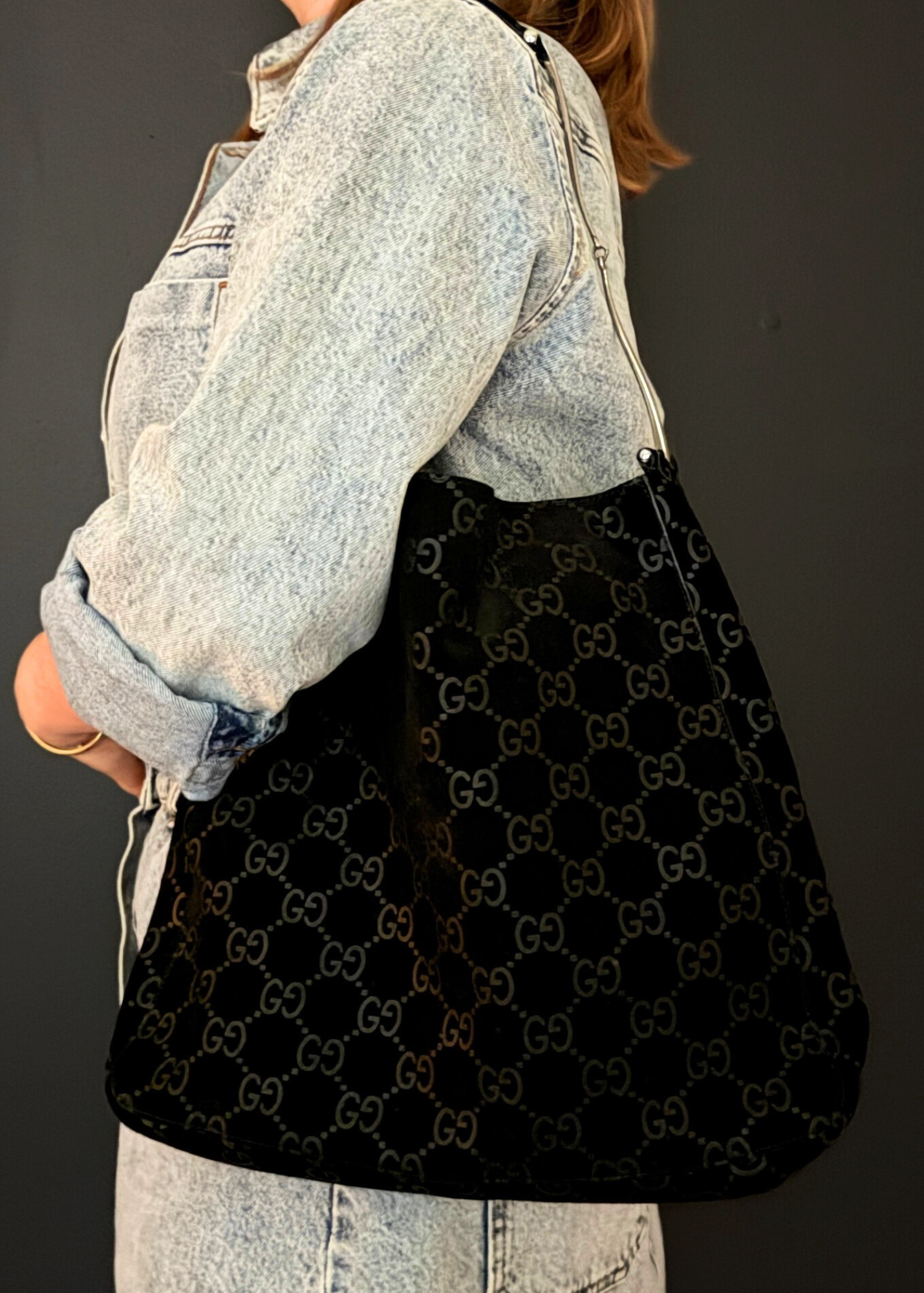 Person wearing a black vintage suede Gucci bag with a dark background