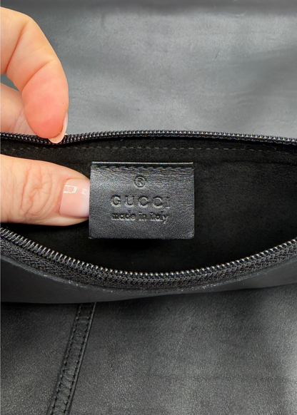Close-up of a Gucci bag with a hand holding the interior tag.