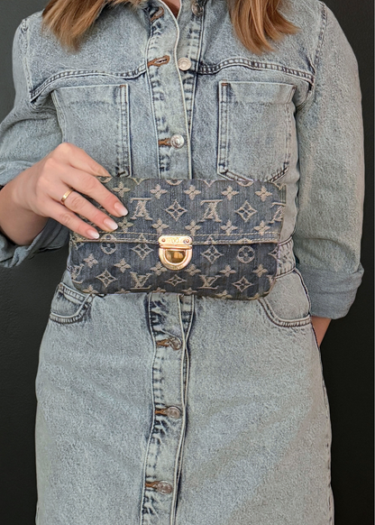 Person wearing a denim jacket with a vintage Louis Vuitton denim monogram pochette clutch