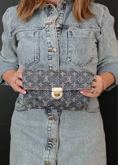 Person holding a Louis Vuitton monogram bag against a black background