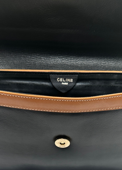 Close-up of a black leather bag with brown trim and Celine logo.