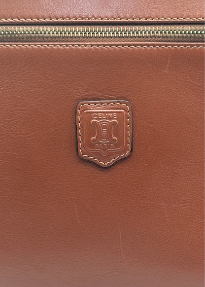 Close-up of a brown leather bag with a brand logo on a matching brown background