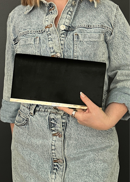 Person wearing a denim jacket holding a black vintage Gucci clutch bag.