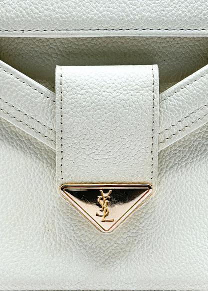 Close-up of a white leather handbag with a gold triangle emblem featuring a Yves Saint Laurent YSL logo.