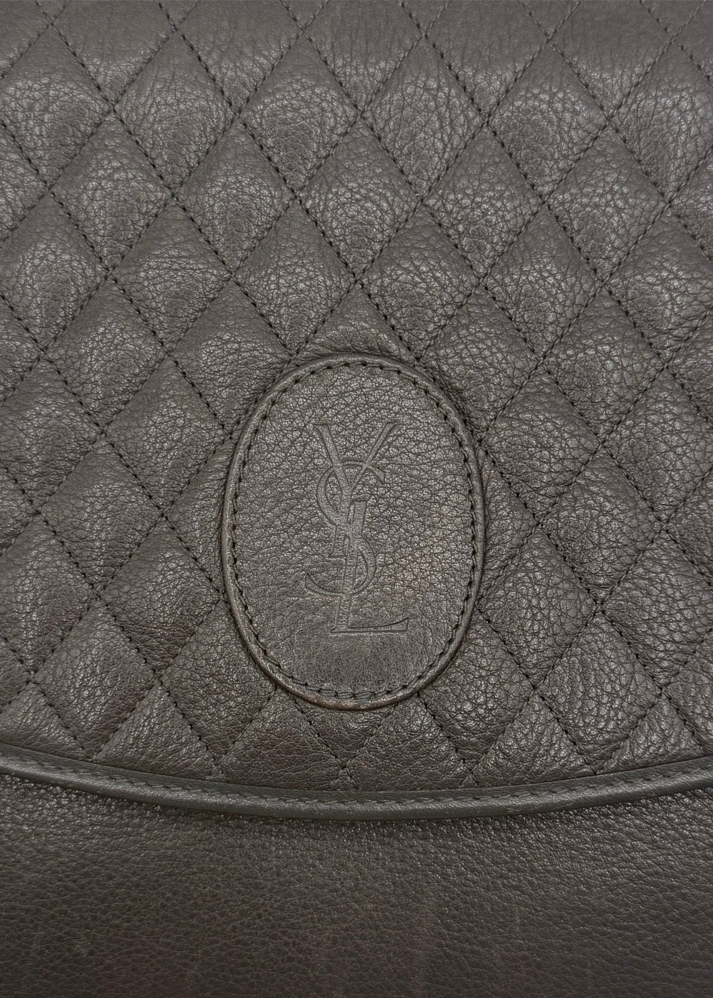Close-up of a quilted leather bag with a YSL brand logo.