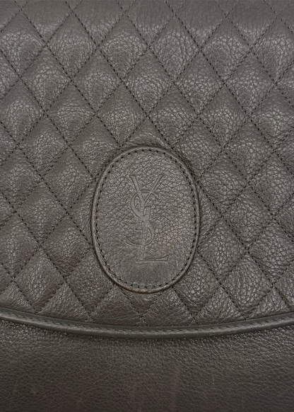 Close-up of a quilted leather bag with a YSL brand logo.