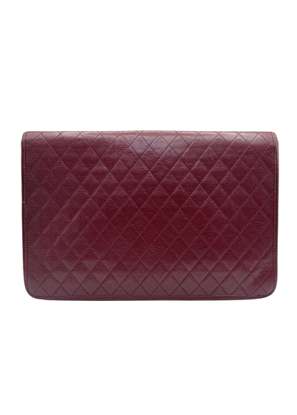 Vintage Yves Saint Laurent quilted burgundy leather clutch against white background