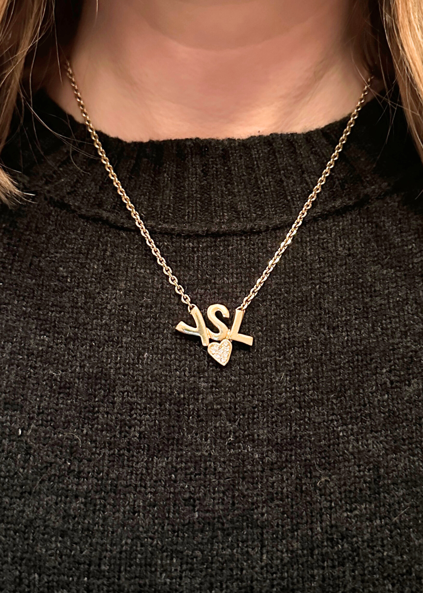 Gold YSL necklace with a heart-shaped pendant on a black background