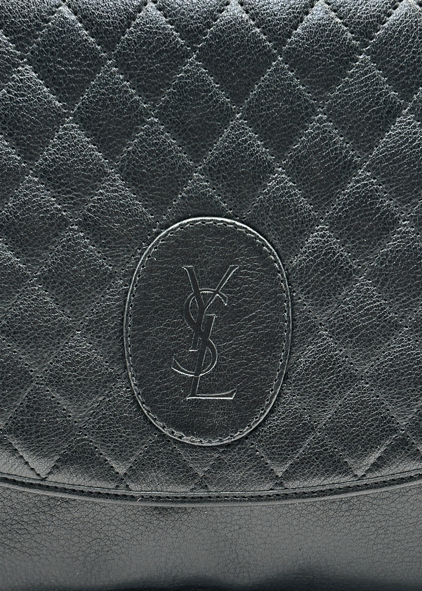 Close-up of a black quilted leather YSL bag with a brand logo.
