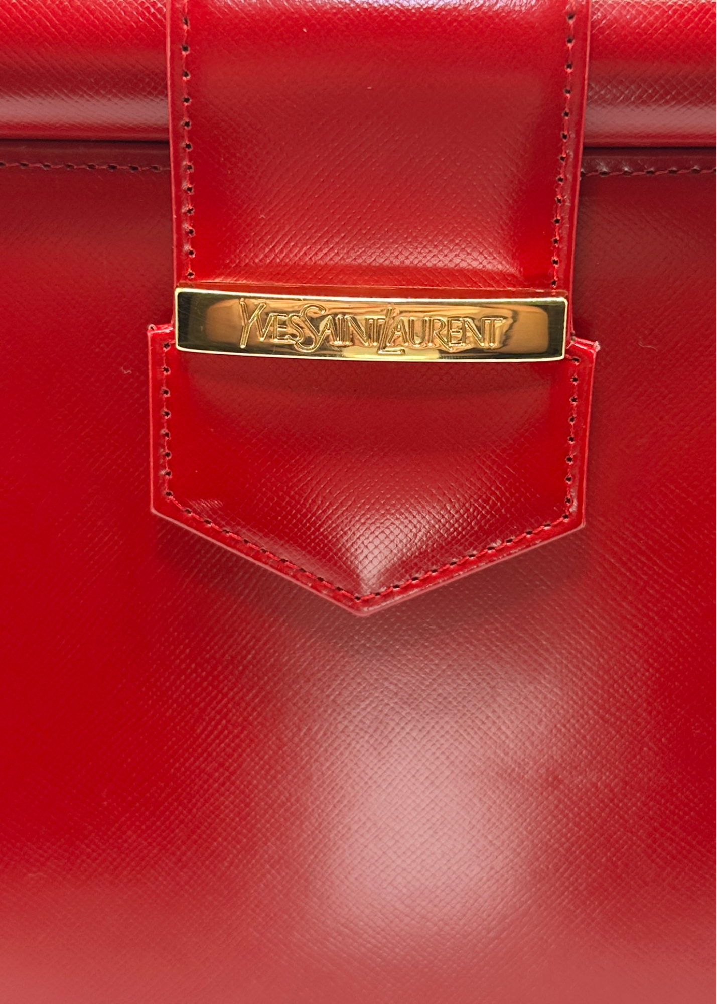 Red handbag with gold Saint Laurent logo on a red background