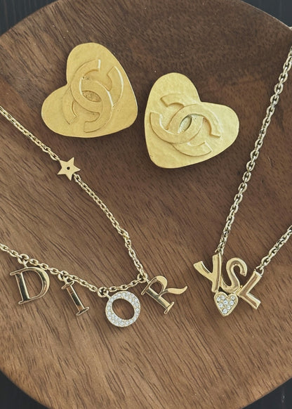 Gold heart-shaped Chanel earrings and necklaces on a wooden surface